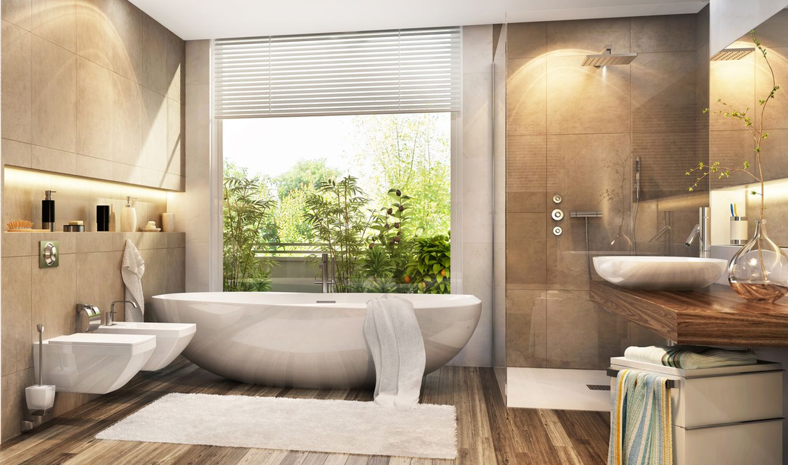 Une salle de bains moderne aux tons beiges comprend une grande baignoire ovale près d'une fenêtre, une douche à l'italienne et un meuble sous lavabo en bois.