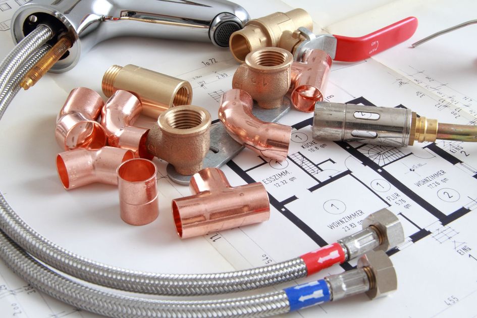 Raccords de plomberie en cuivre et tuyaux en acier inoxydable tressé disposés sur un plan technique.
