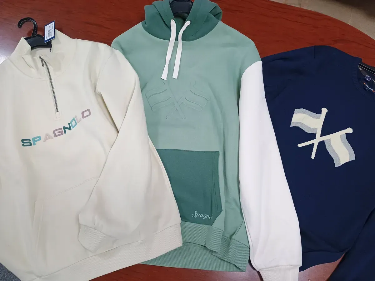 Zapatos de cuero marrón, camisa a cuadros, jeans y un cinturón rojo sobre una superficie de madera.