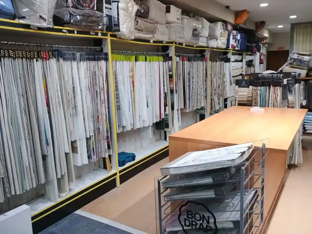 La mano de una persona toca una tela marrón plisada con borde gris. La tela está sobre una superficie oscura.