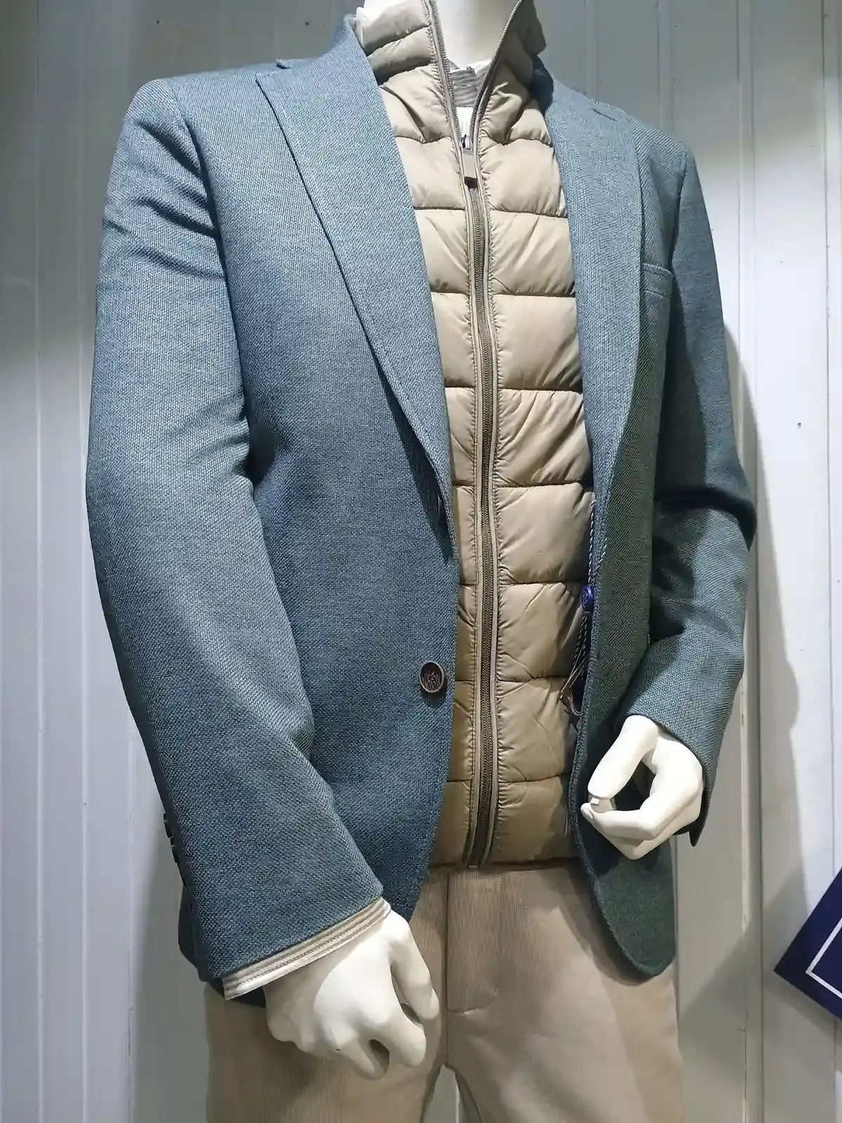 Atuendo dispuesto sobre madera: camisa a cuadros, suéter marrón, pantalones color canela, botas y un gorro gris.