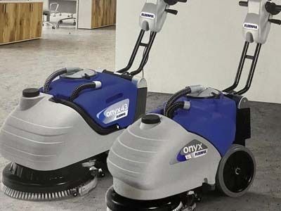 Dos máquinas de limpieza están una al lado de la otra sobre un piso de concreto.