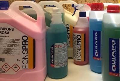 Varias botellas de productos de limpieza están alineadas sobre una mesa.
