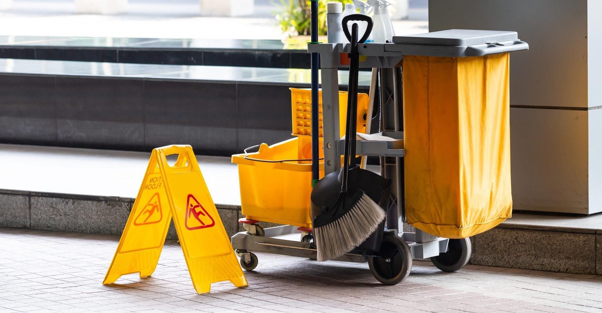 Una señal de precaución amarilla está al lado de un carrito de limpieza.