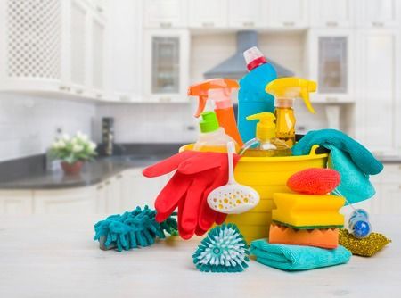 Un cubo lleno de productos de limpieza en una cocina.