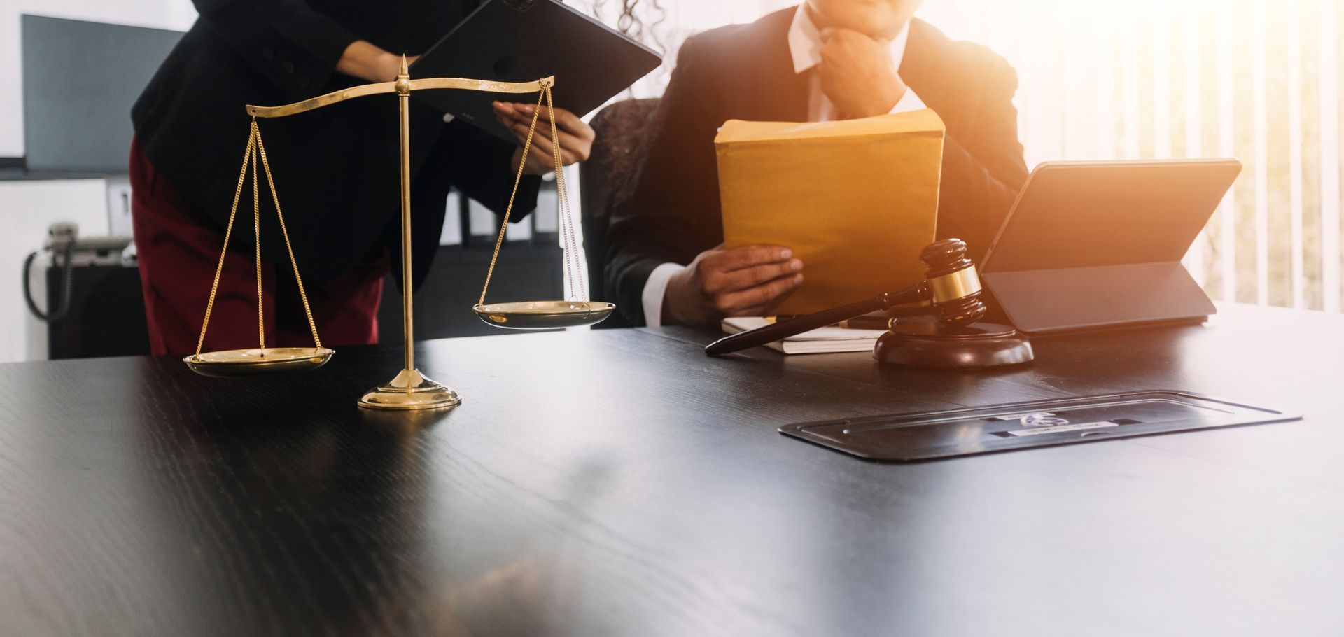 Abogados en una mesa con una balanza, un mazo, archivos y una computadora portátil.