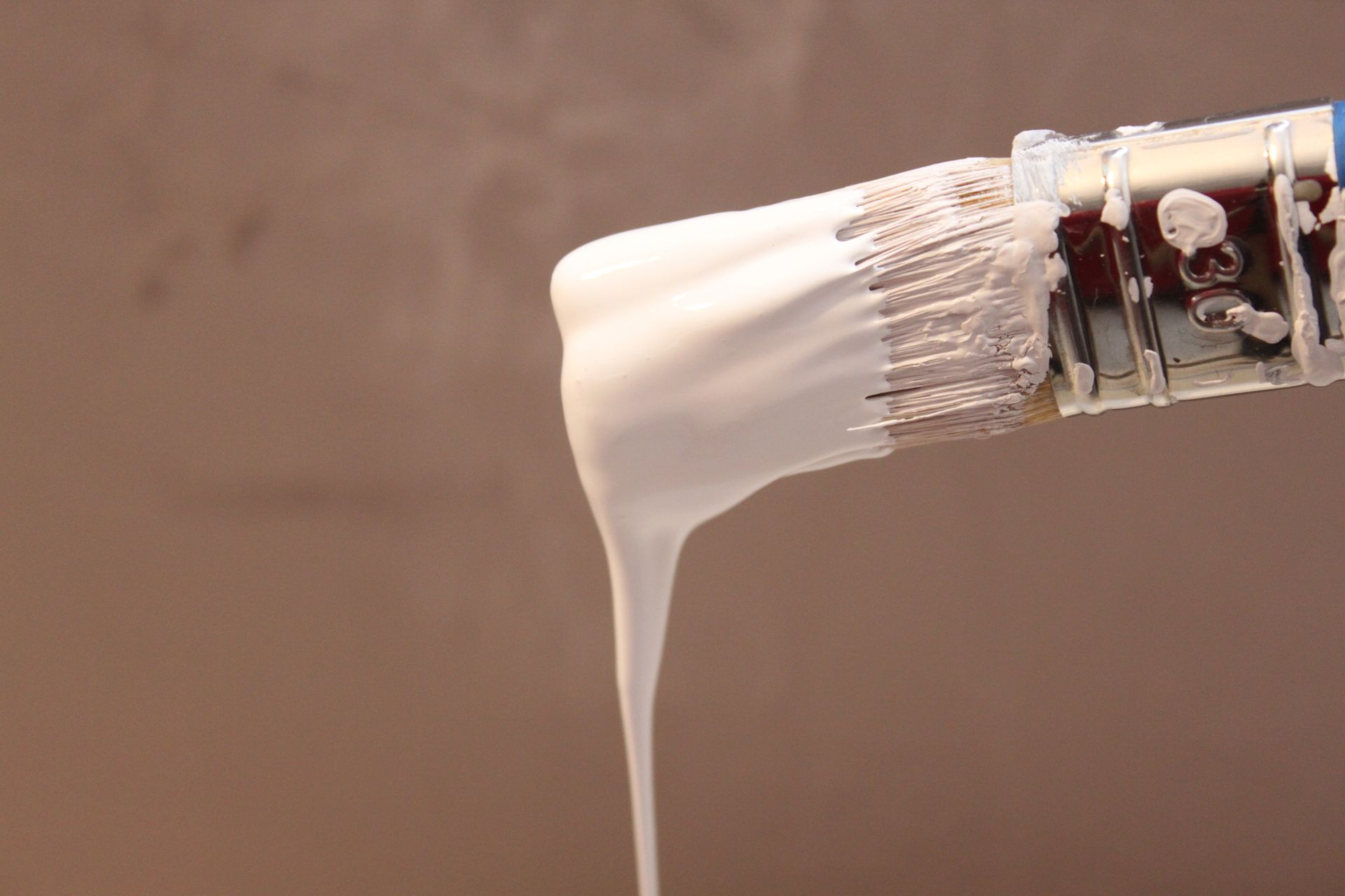 Pinceau dégoulinant de peinture blanche.