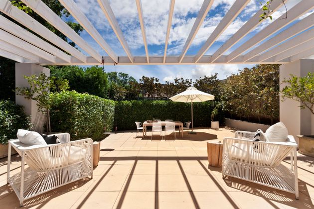 Terrasse ensoleillée avec une pergola blanche.