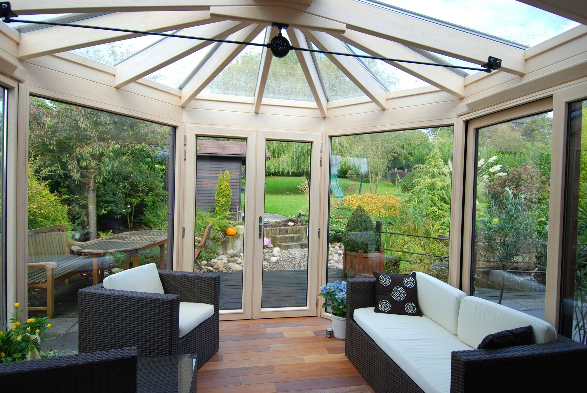 Véranda avec mobilier en osier donnant sur un jardin.