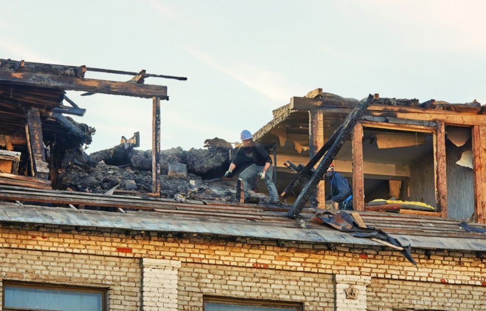 Ausgebranntes Gebäudedach mit Brandschäden und Trümmern auf einem Backsteinbau