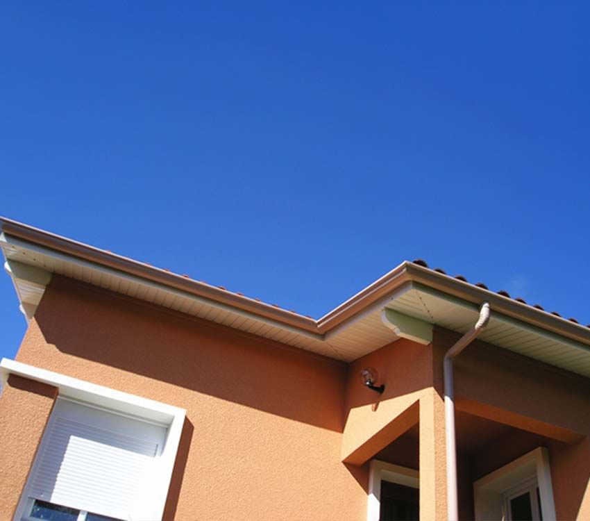 Maison orange avec des boiseries et une toiture blanches se détachant sur un ciel bleu clair.