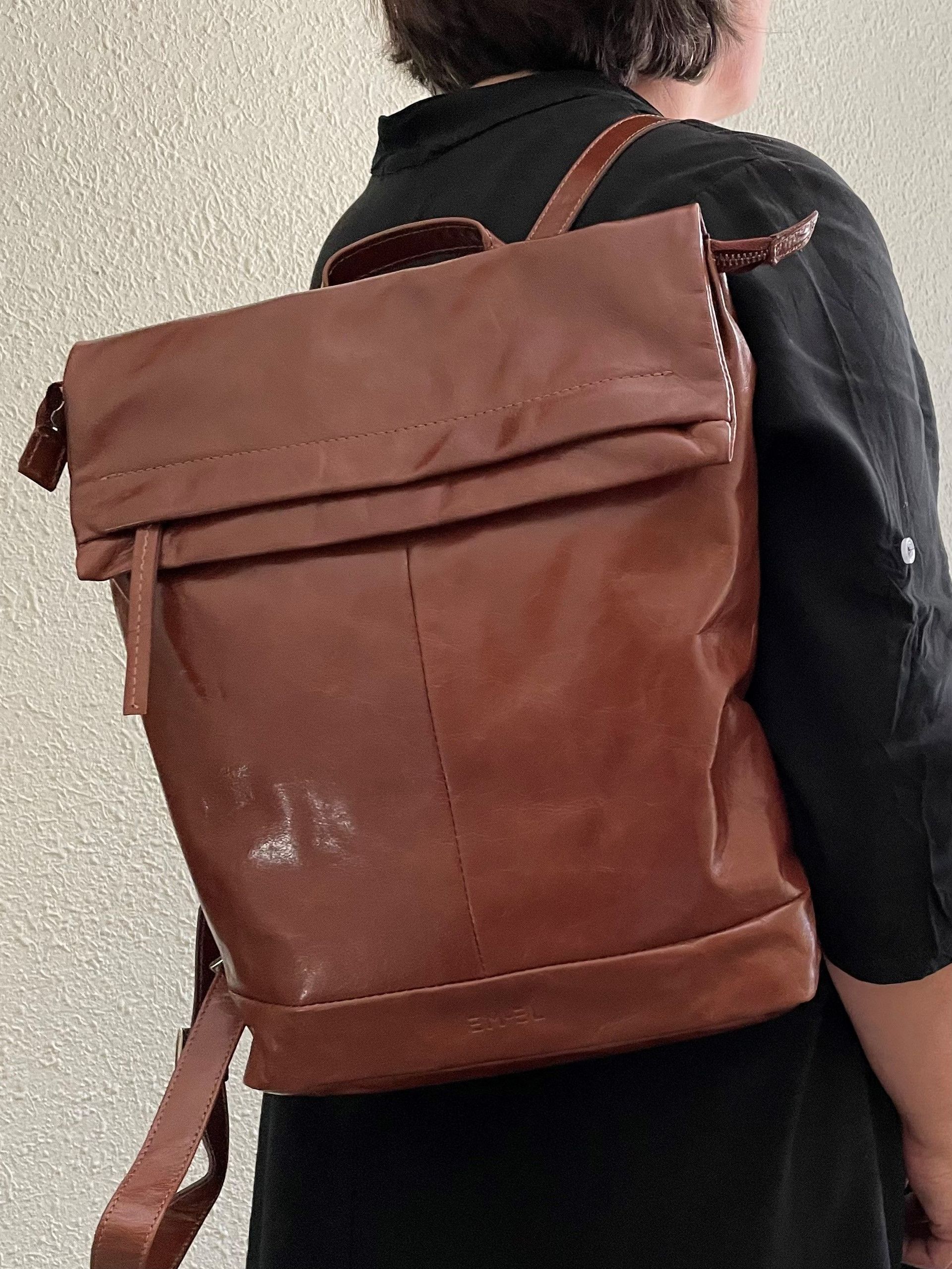 Eine Frau trägt einen braunen Lederrucksack auf dem Rücken