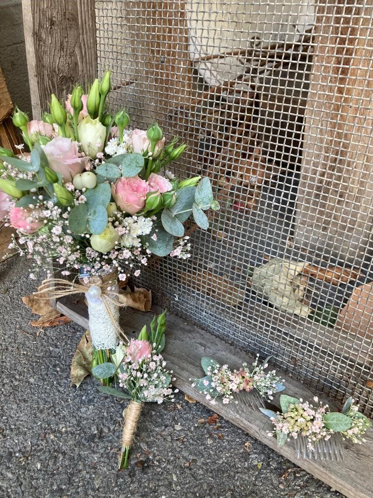 Ein Blumenstrauß steht auf einem Holztisch neben einem Maschendrahtzaun.