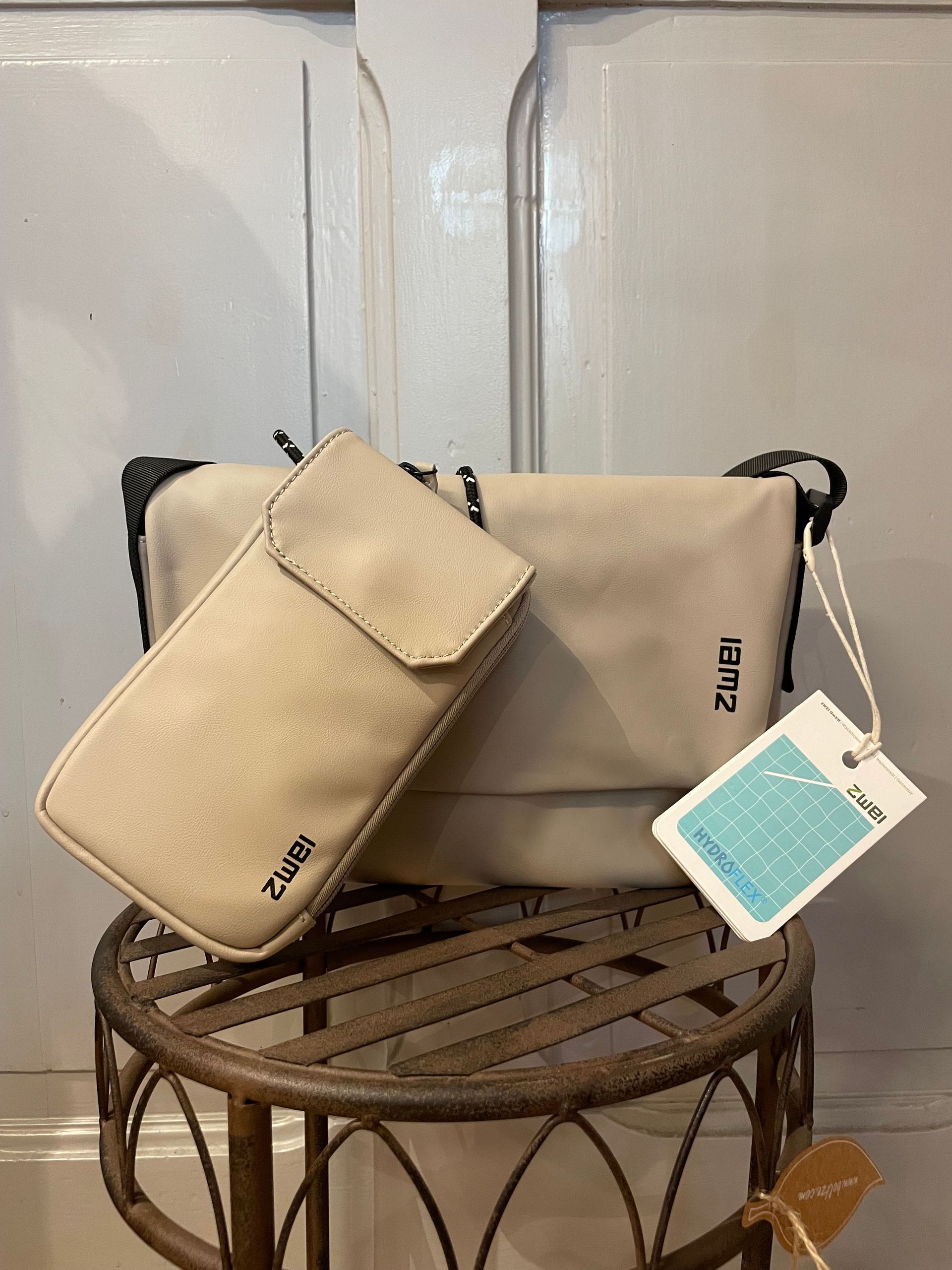 Auf einem Metallhocker liegen eine Handtasche und eine Brieftasche.