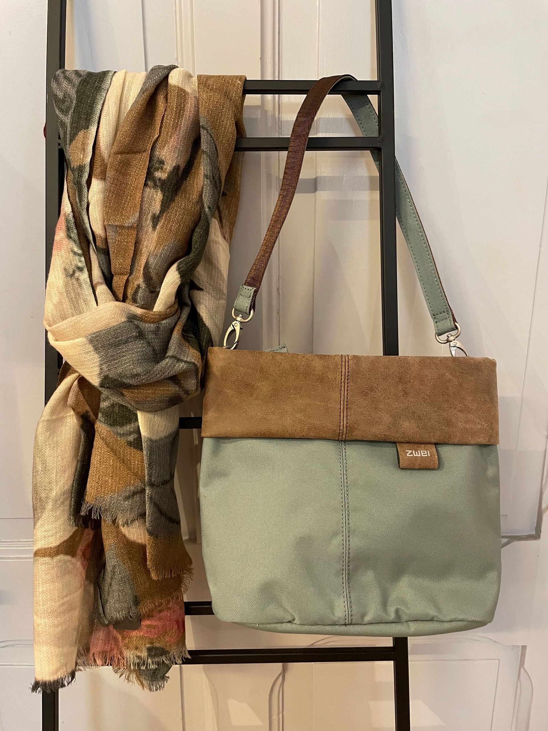 Ein Schal und eine Handtasche hängen an einer Leiter.