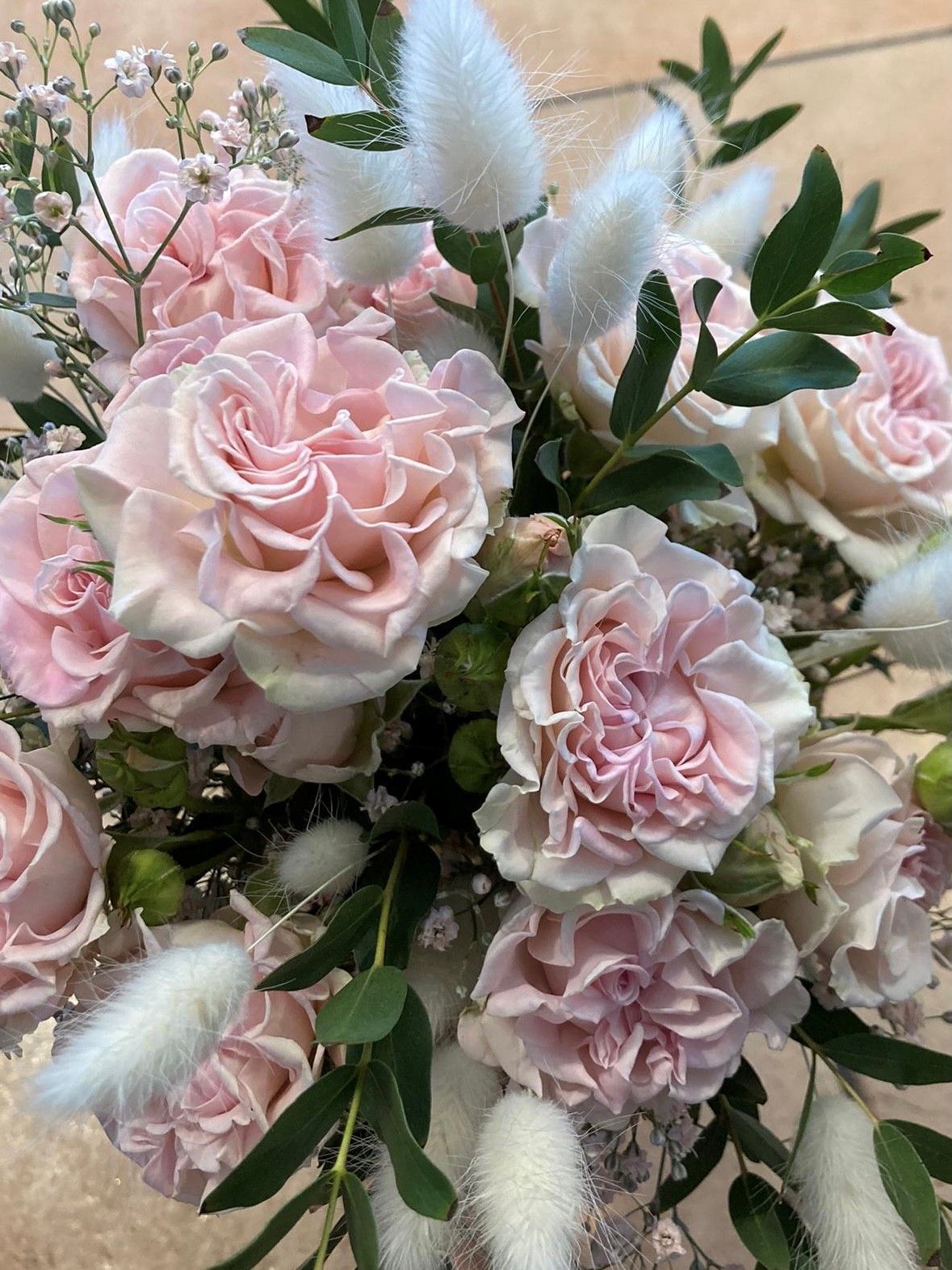 Eine Nahaufnahme eines Straußes rosa Rosen und Nelken auf einem Tisch.