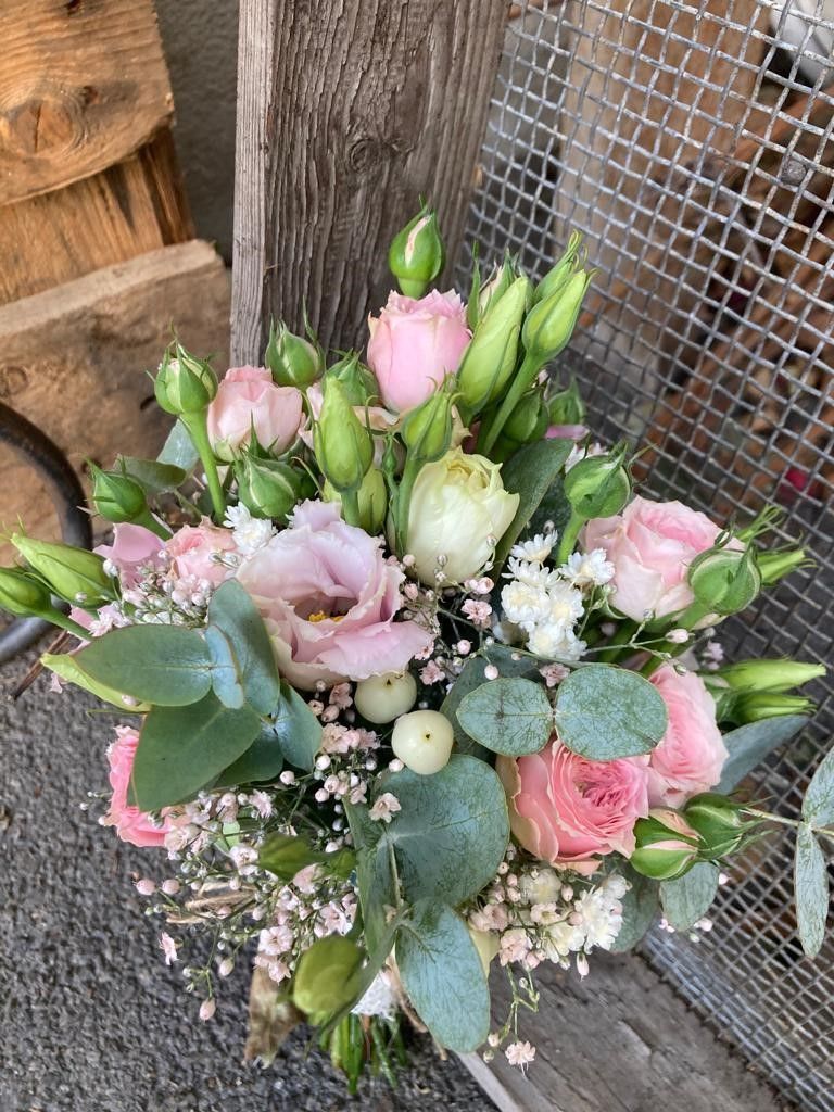 Ein Strauß rosa und weißer Blumen steht auf einem Holztisch.