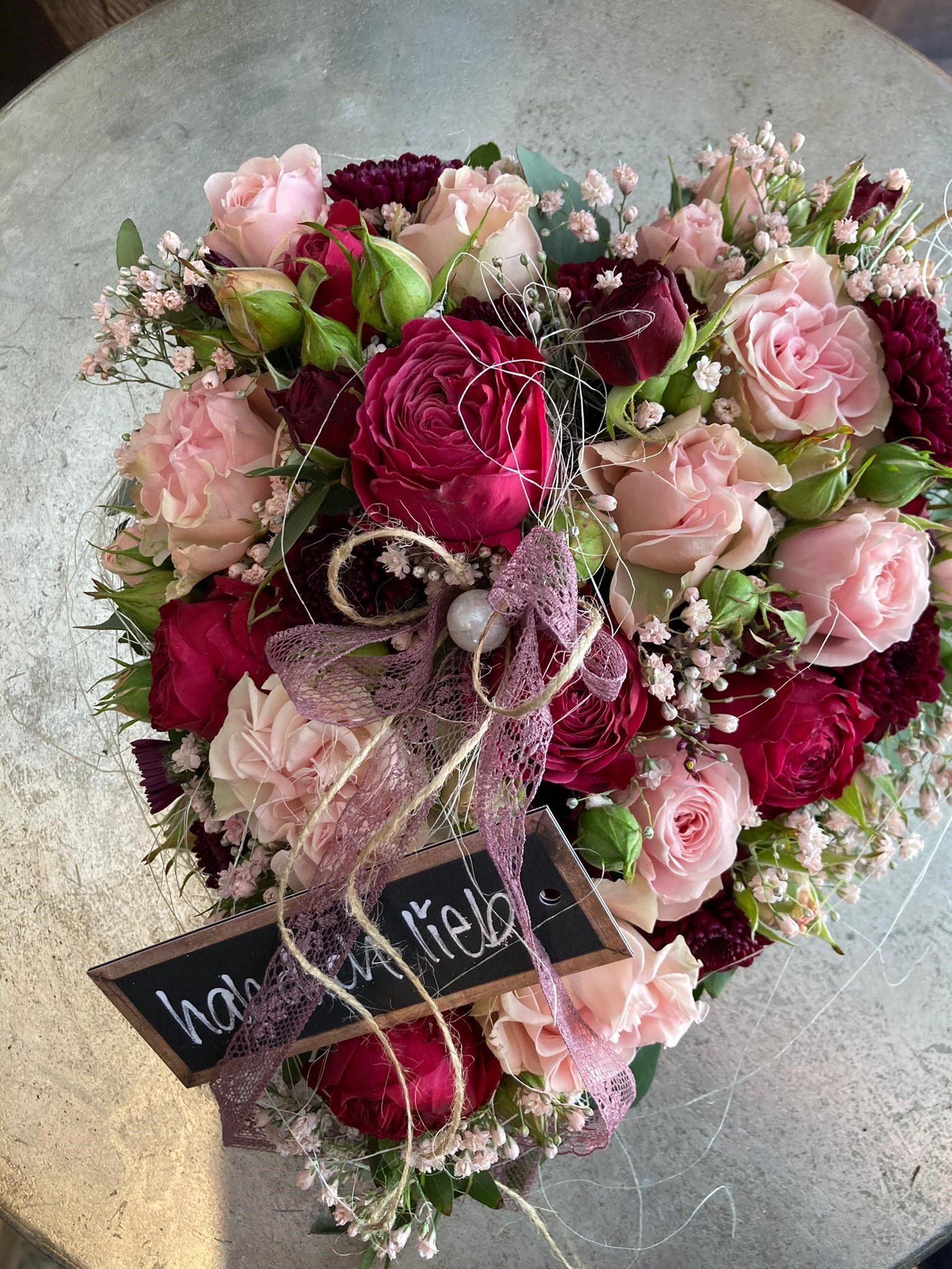 Auf einem Tisch steht ein herzförmiger Blumenstrauß.