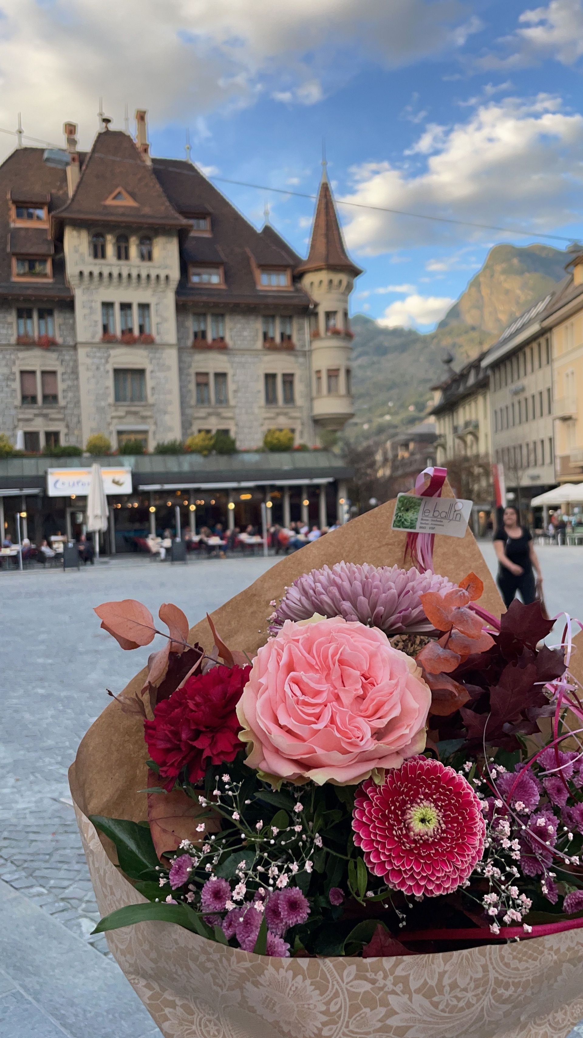 Ein Strauß rosa Blumen liegt auf dem Boden vor einem Gebäude.
