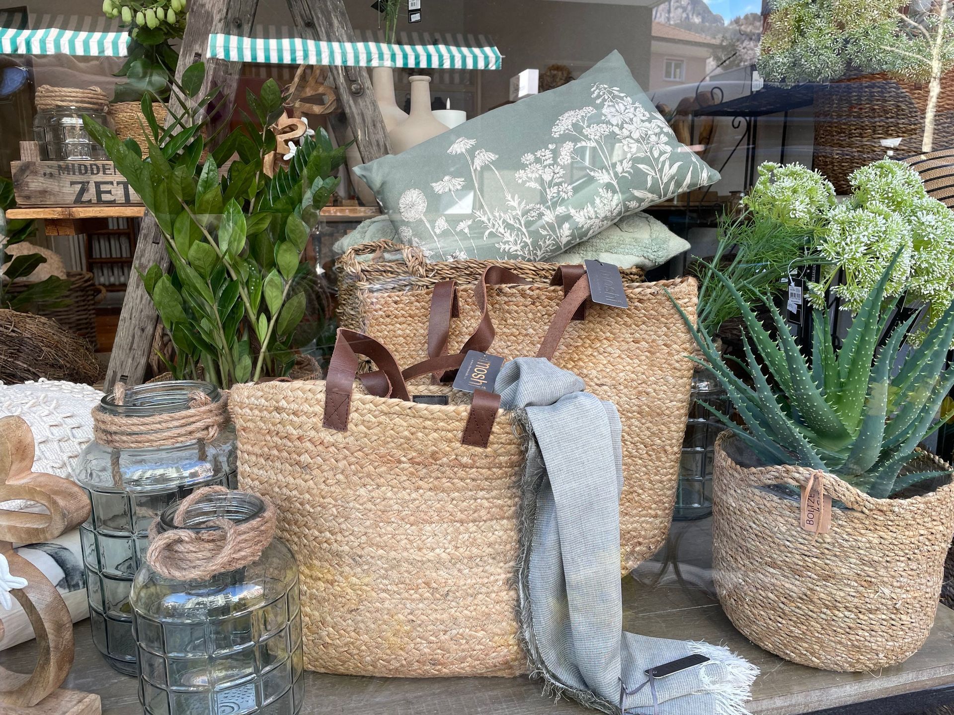 Ein Weidenkorb steht neben Pflanzen auf einem Tisch.