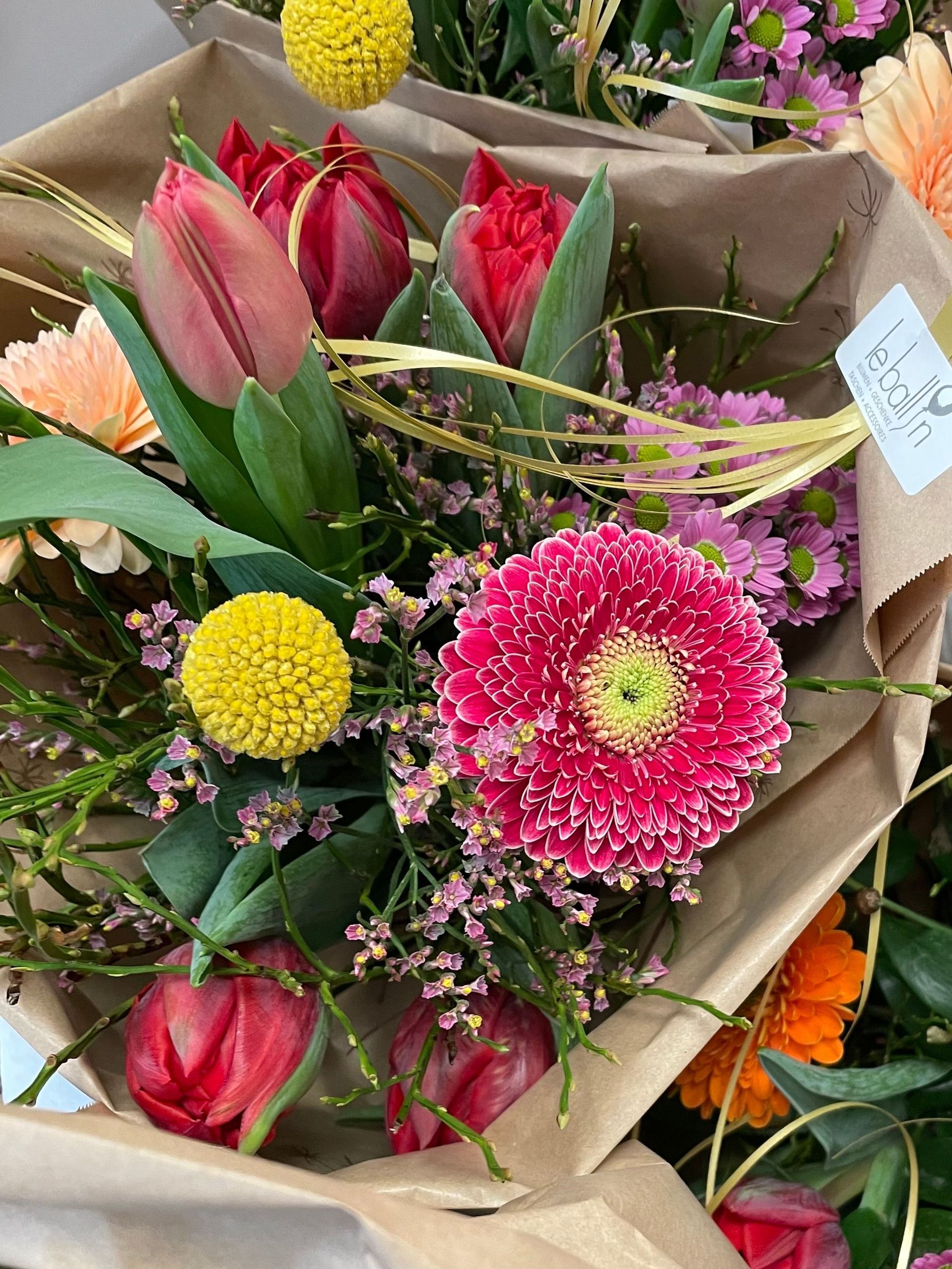 Auf einem Tisch steht ein in braunes Papier eingewickelter Blumenstrauß.