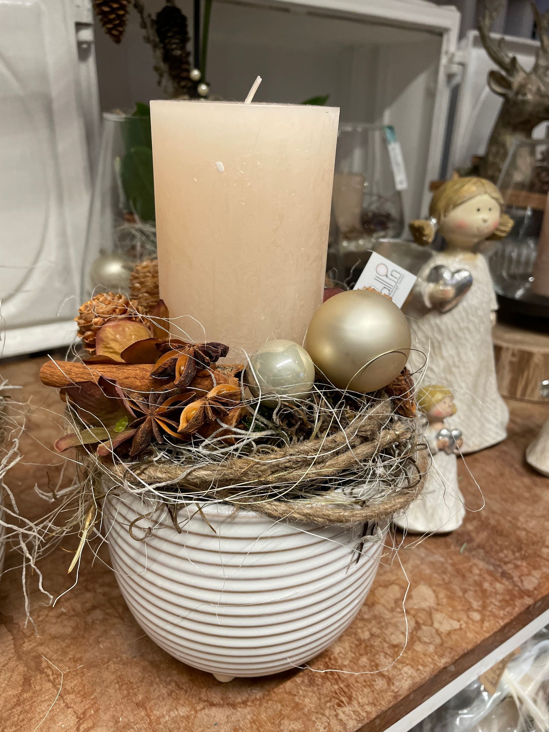 Eine Kerze steht in einer weißen Vase auf einem Tisch.