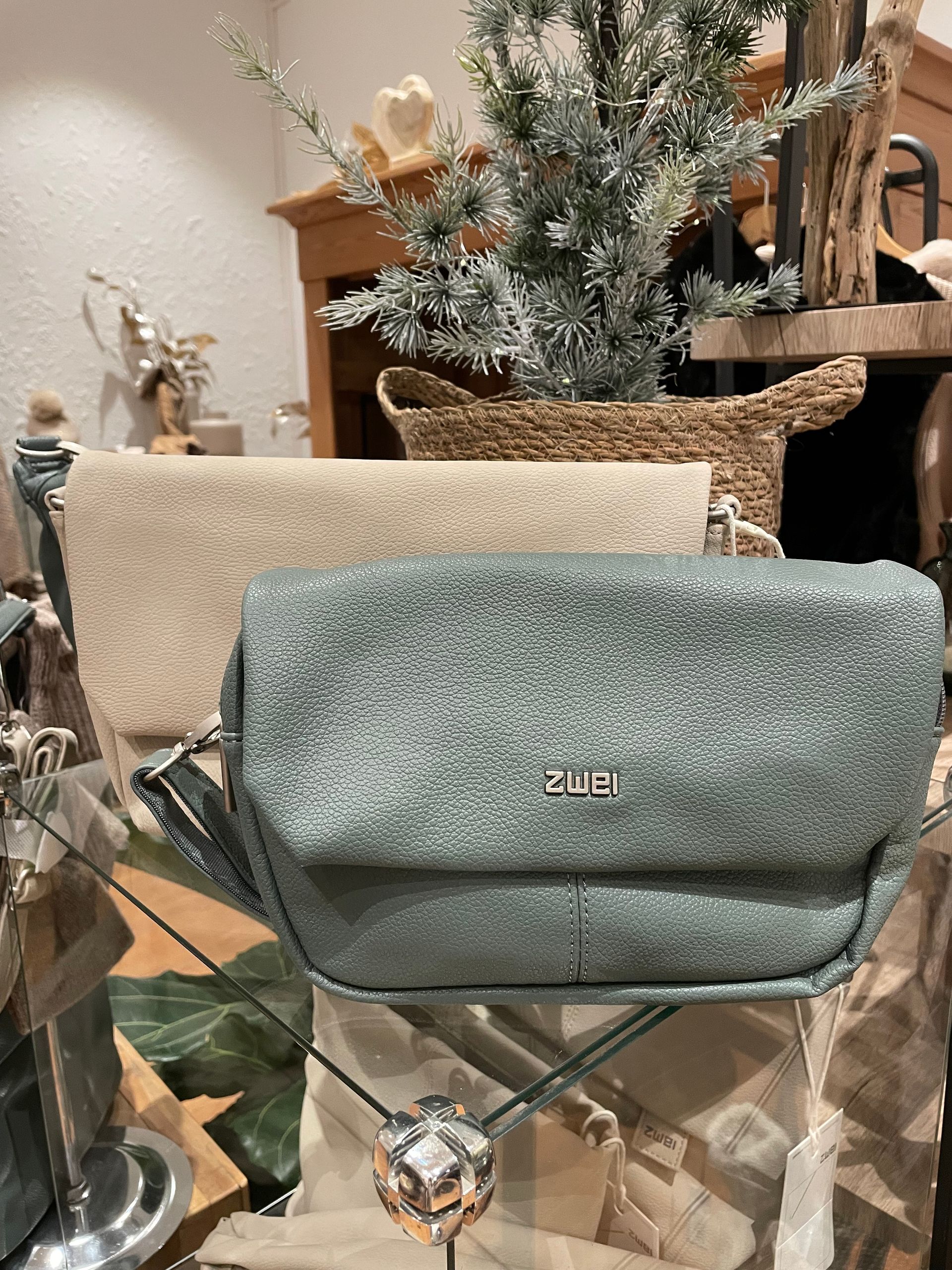 Eine Handtasche liegt auf einem Glastisch neben einem Weihnachtsbaum.