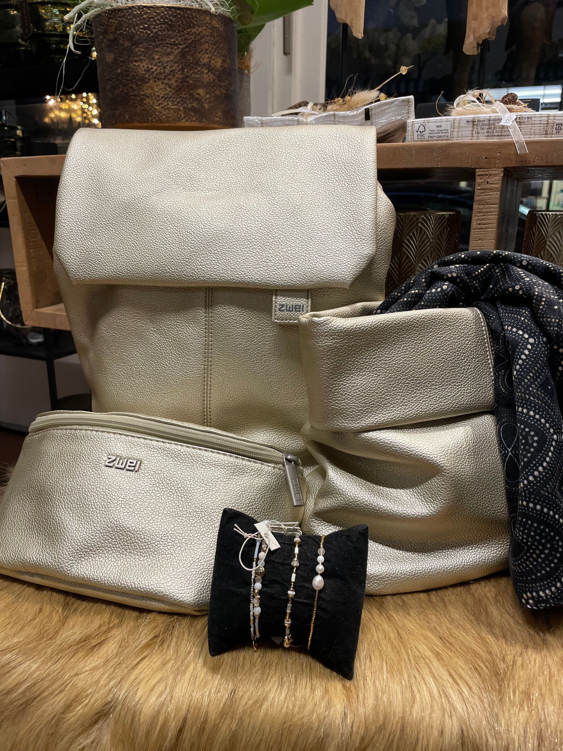 Ein Stapel goldener Taschen und Armbänder liegt übereinander auf einem Tisch.