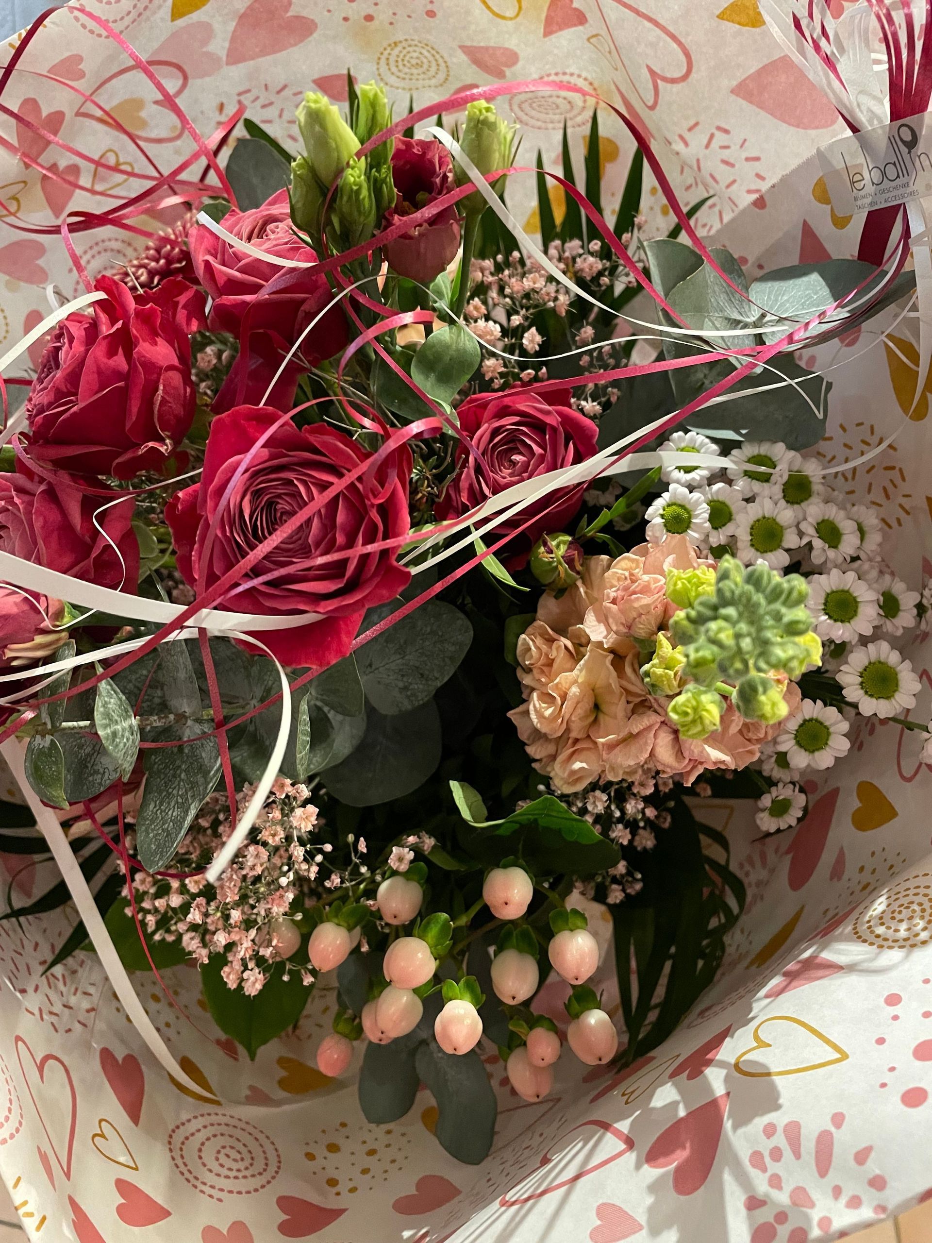 Ein Blumenstrauß in rosa Papier eingewickelt mit Herzen darauf