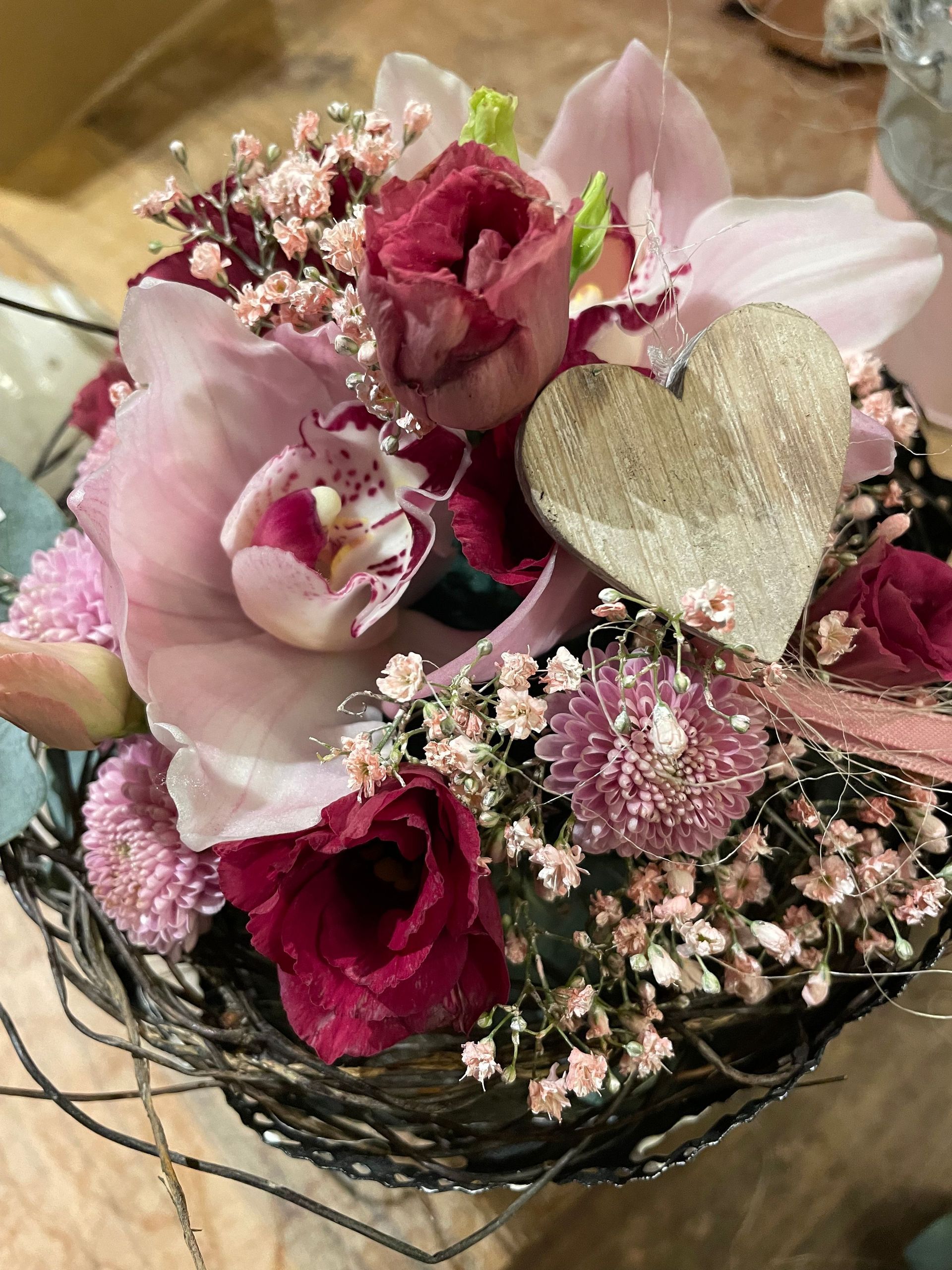 Ein Korb gefüllt mit rosa Blumen und einem Herzen.