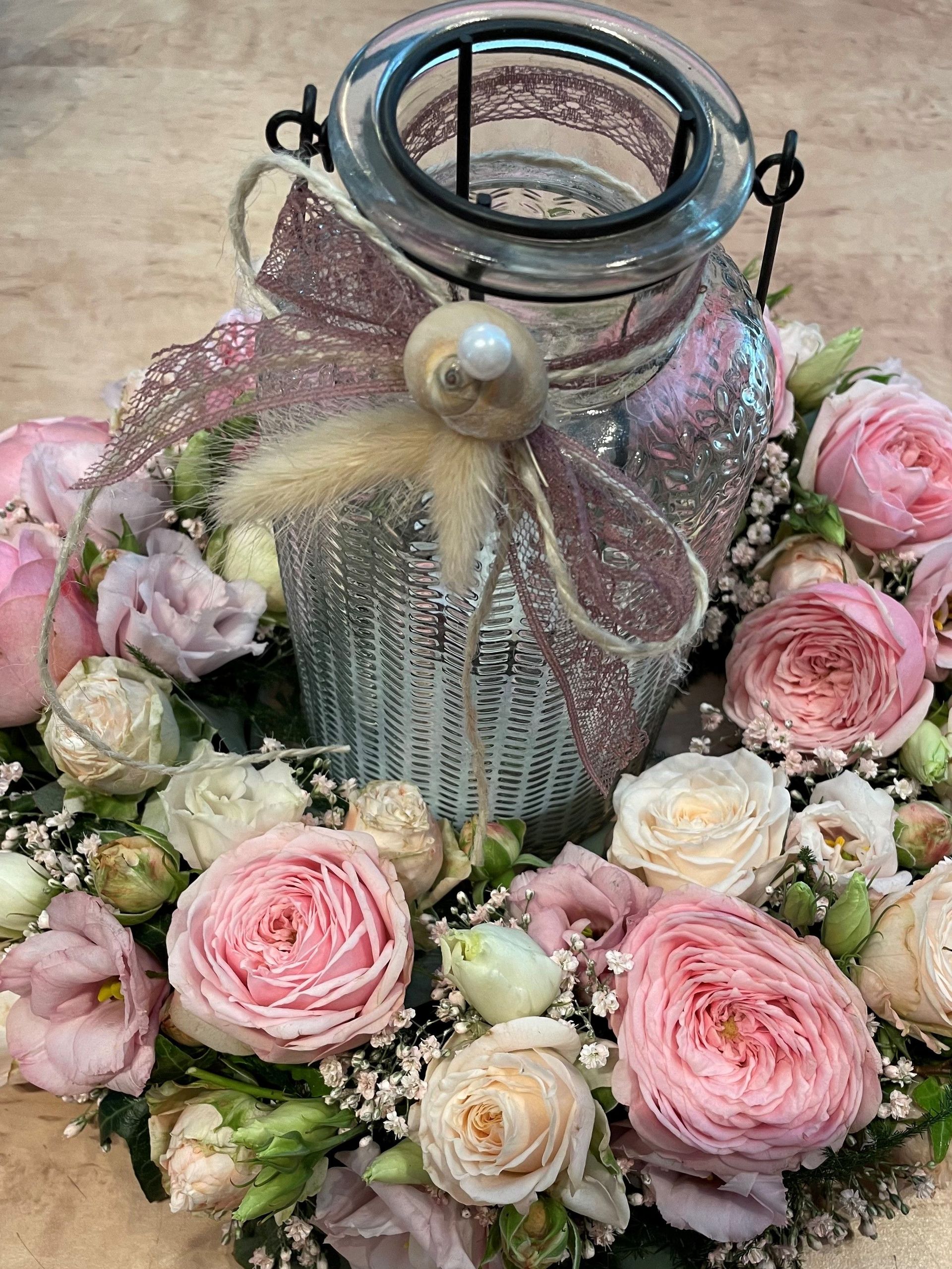 Eine Vase mit rosa Blumen und eine Laterne auf einem Tisch.