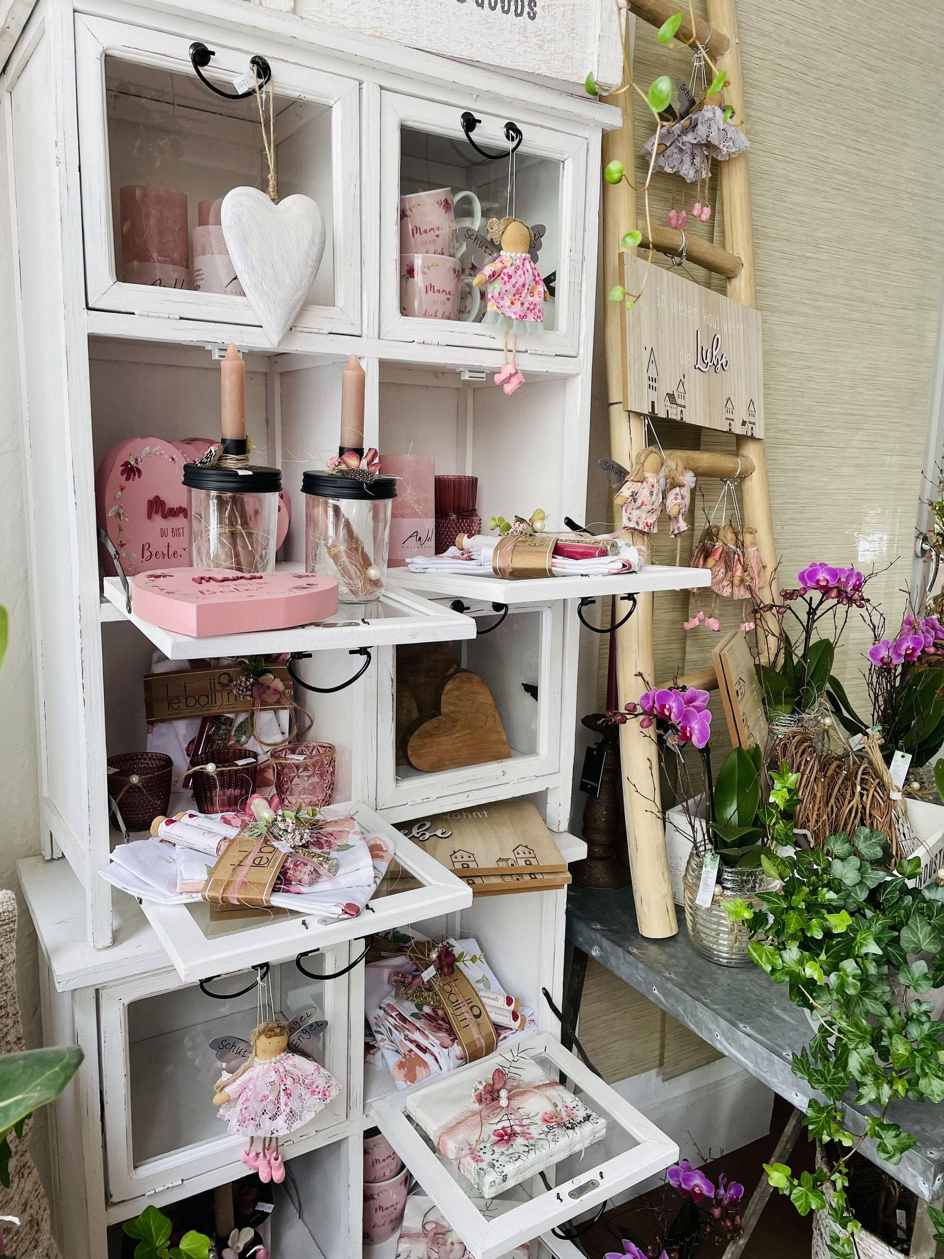 Ein weißer Schrank voller Gegenstände und Blumen.