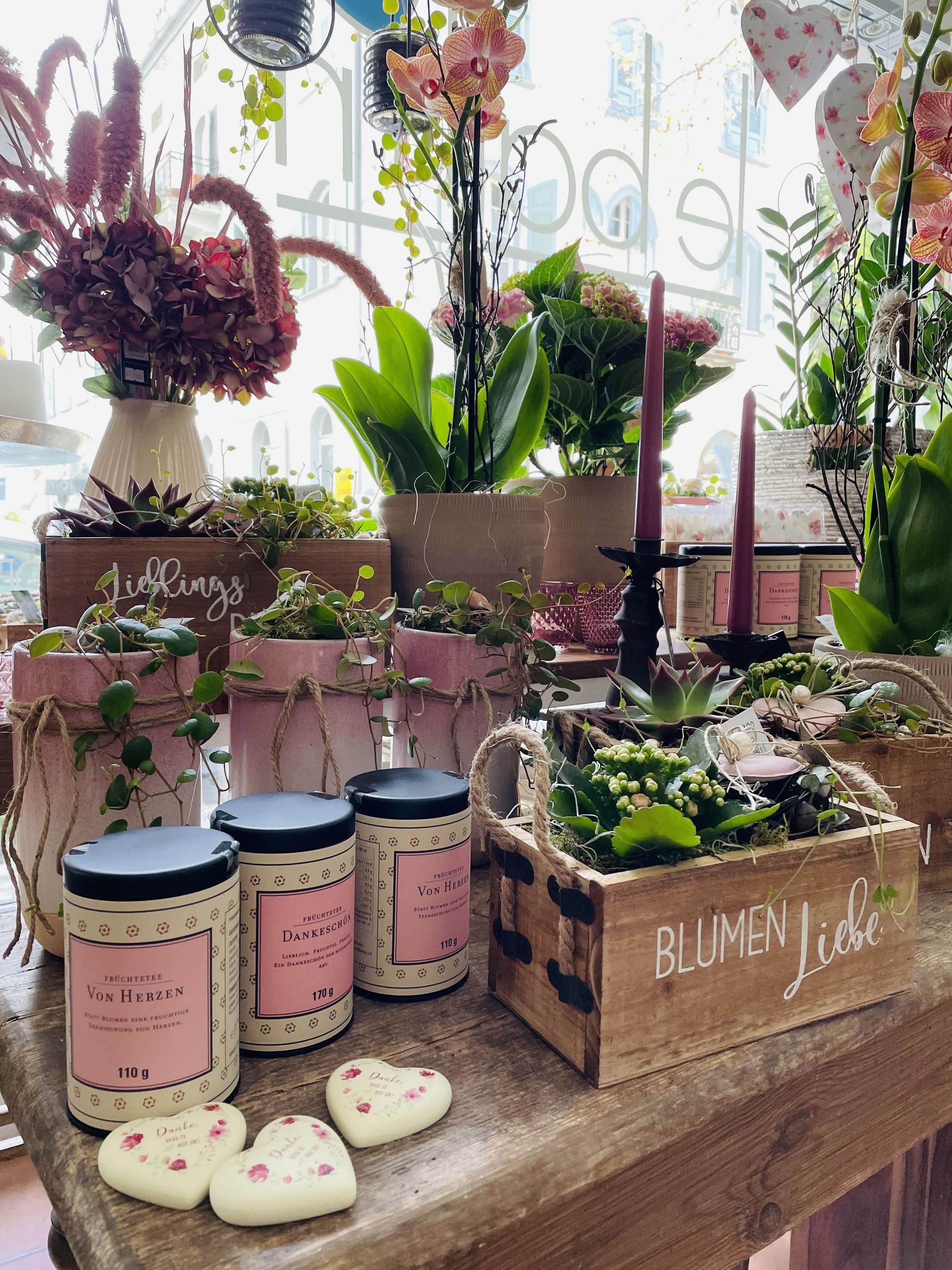 Ein Tisch mit vielen Topfpflanzen und Kerzen darauf.