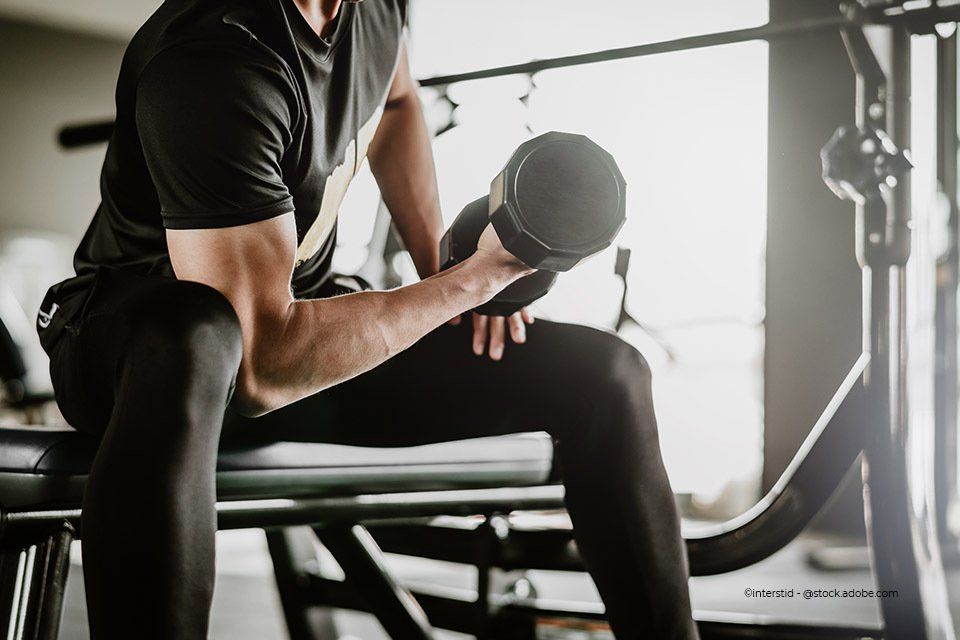 Junger Mann trainiert mit Hanteln in der Körpermanufaktur