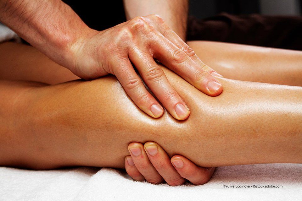Mitarbeiter der Körpermanufaktur massiert die Unterschenkel einer Frau