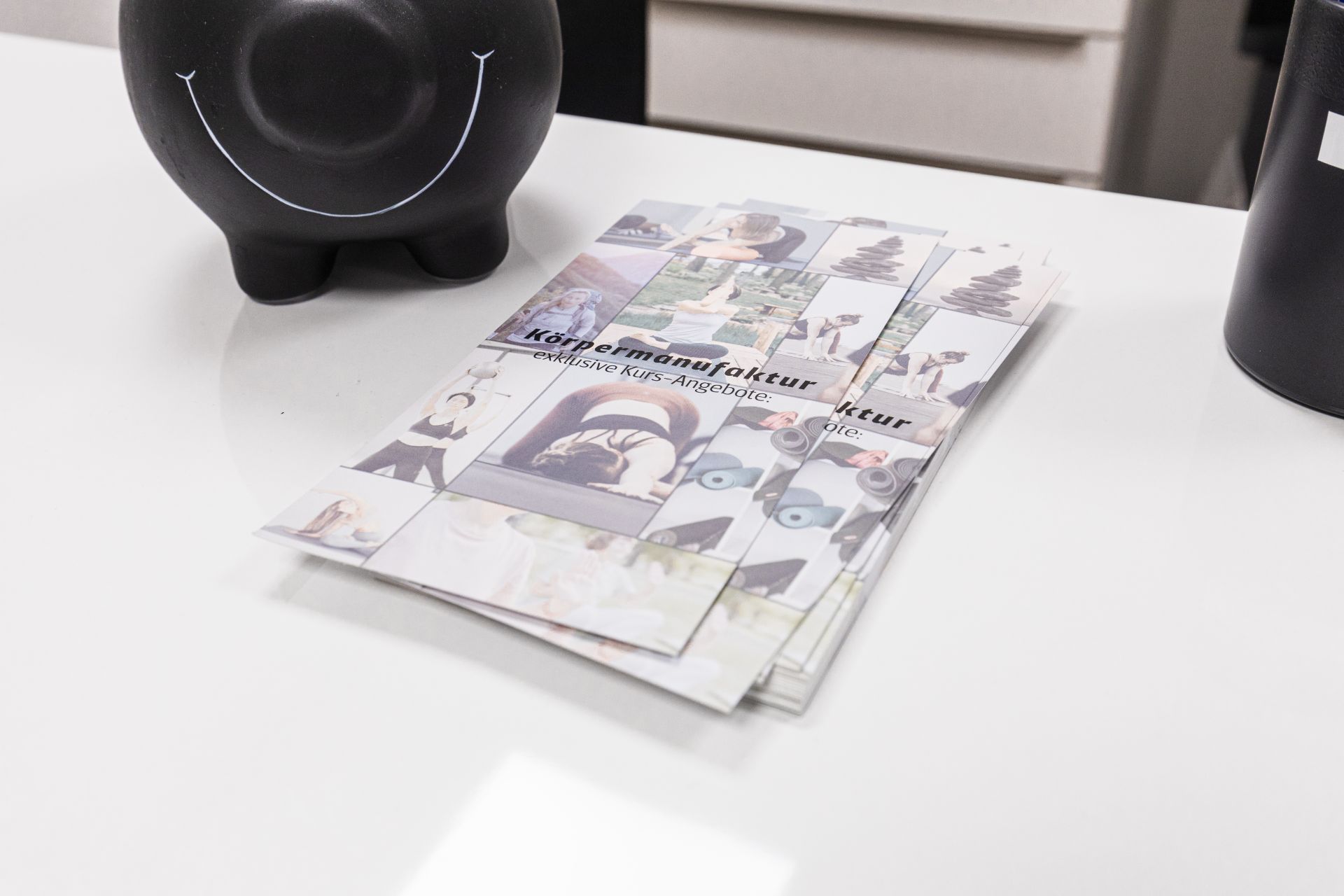 Tisch mit Sparschwein und Broschüren über die Körpermanufaktur