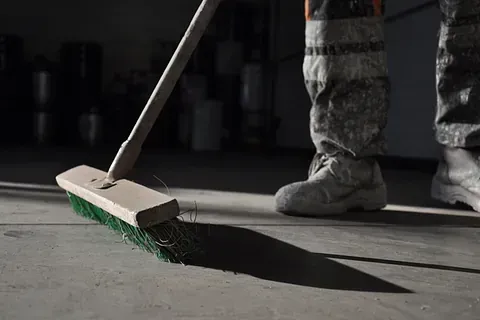 Una persona está barriendo el suelo con una escoba.