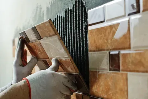 Una persona está instalando azulejos en una pared.