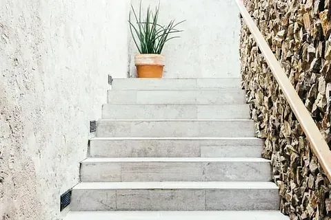Un conjunto de escaleras que conducen a un muro de piedra con una planta en maceta en los escalones.