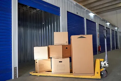 Una carretilla amarilla llena de cajas de cartón en un almacén.