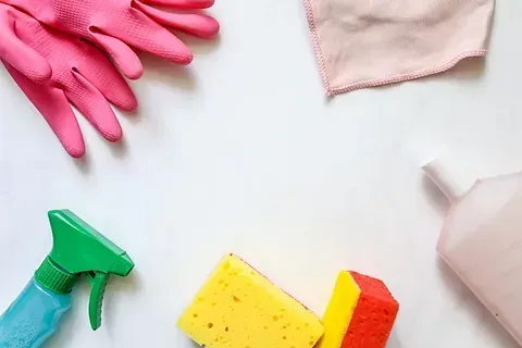 Hay guantes, esponjas, botellas de spray y una toalla sobre la mesa.