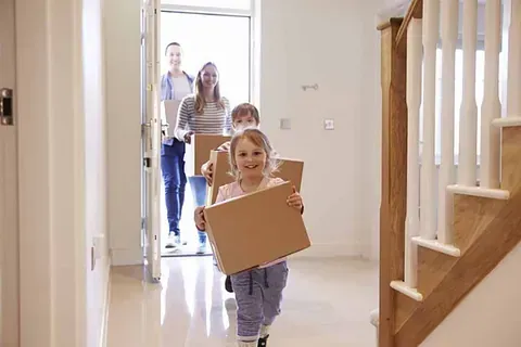 Una familia lleva cajas de cartón a su nuevo hogar.