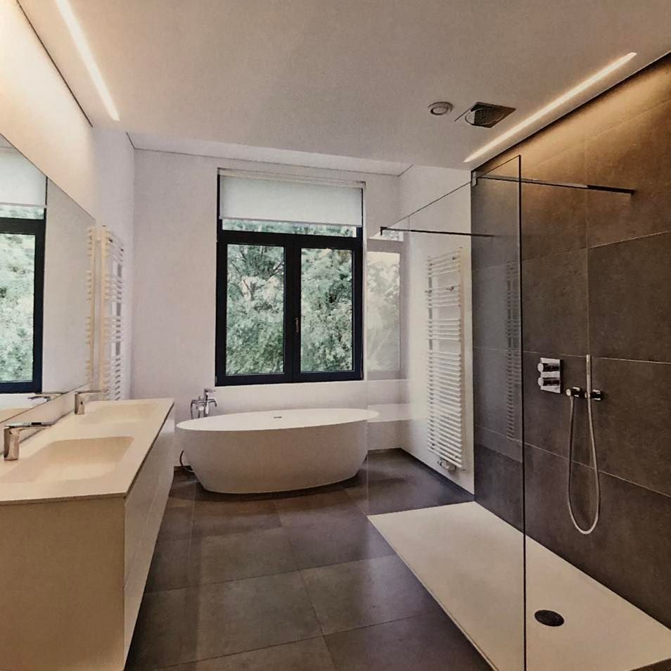 Salle de bains moderne avec baignoire îlot, double vasque, douche à l'italienne et grandes fenêtres.