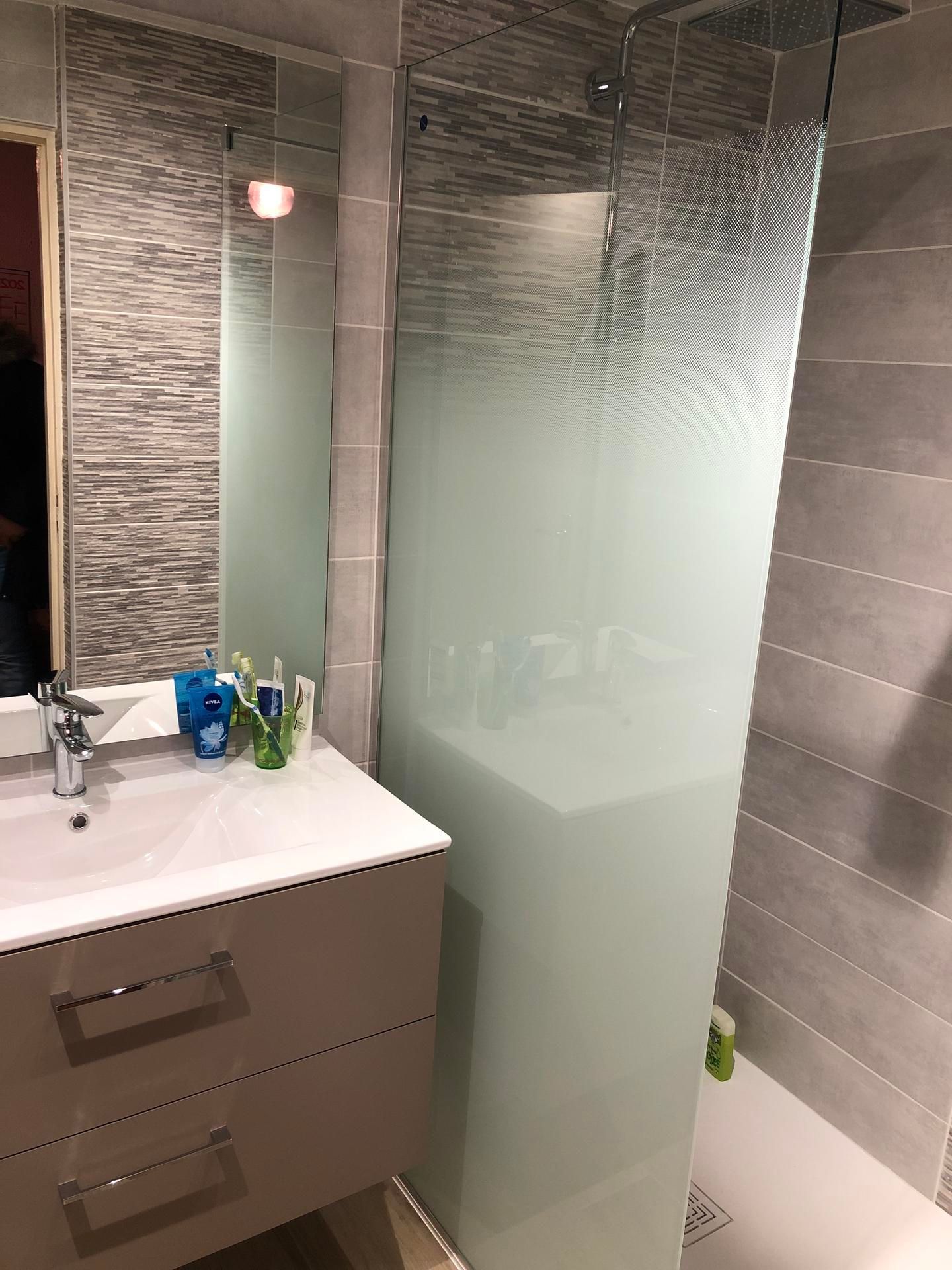Petite salle de bains moderne avec meuble vasque et paroi de douche en verre dépoli.