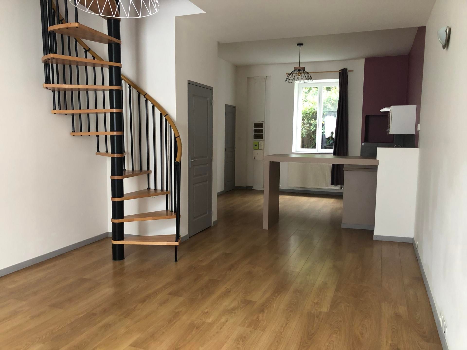 Salon moderne avec parquet, escalier en colimaçon et coin cuisine à l'arrière.