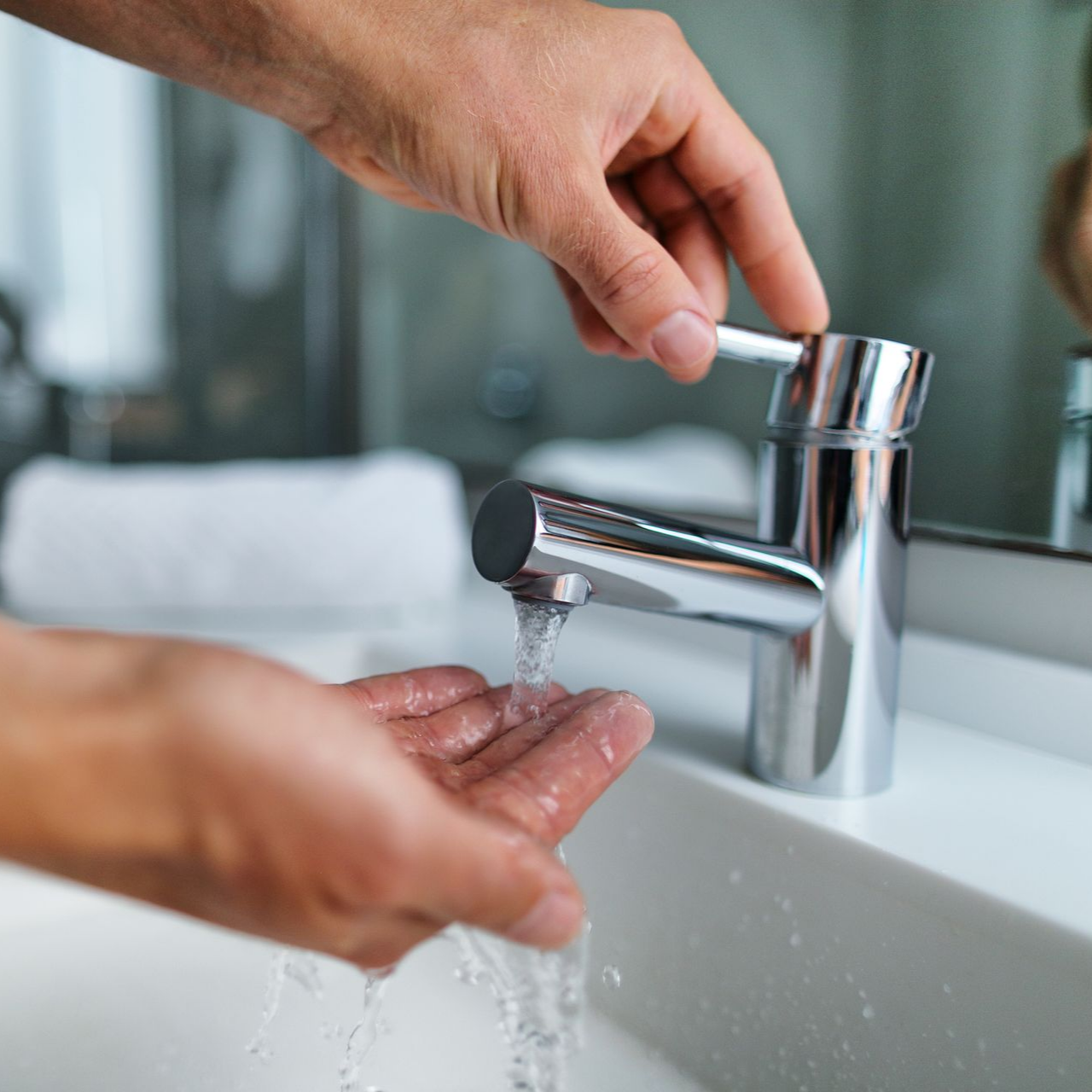 Une personne qui ouvre le robinet d'un lavabo.