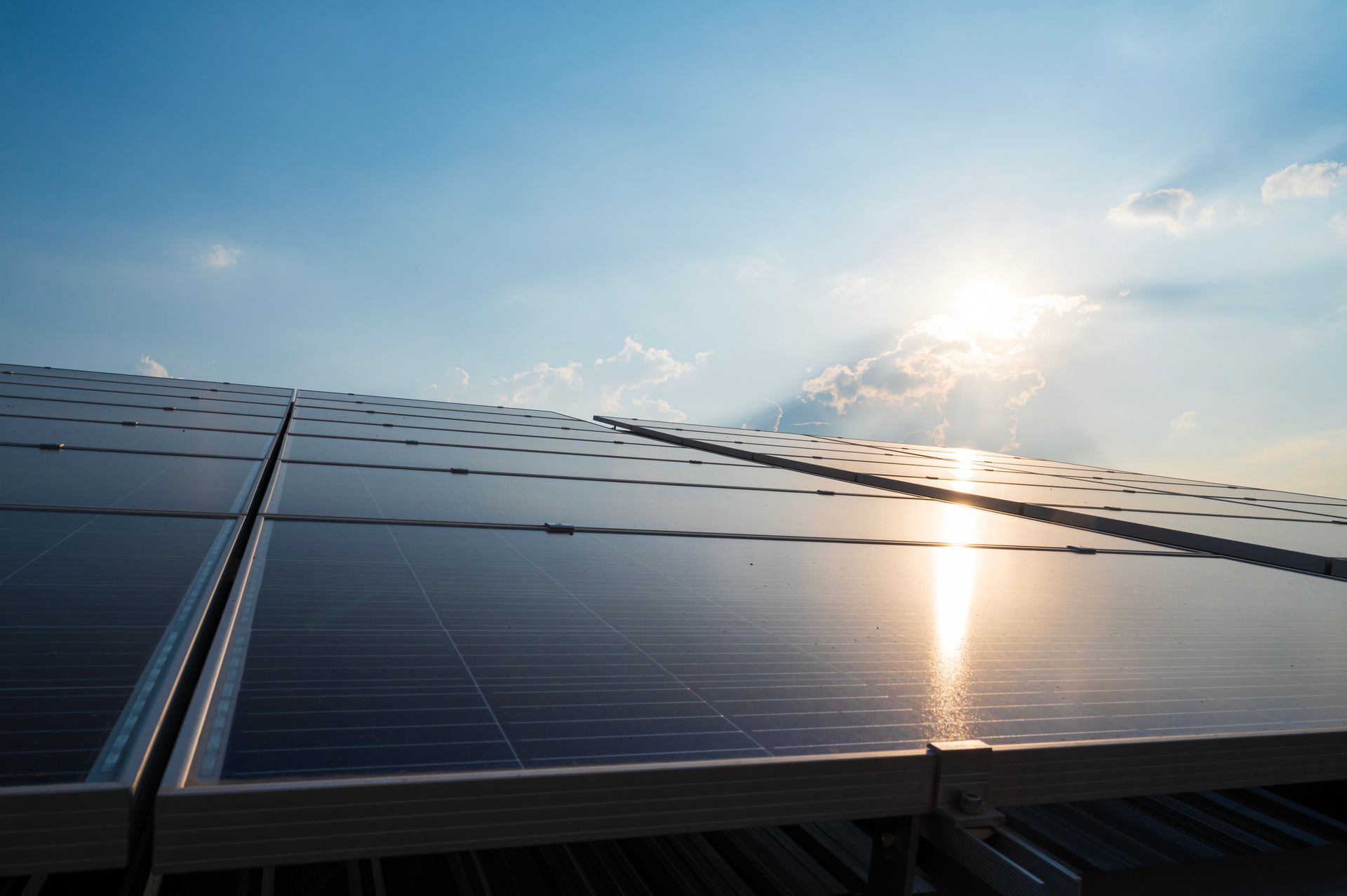 Gros plan sur des panneaux photovoltaïques illuminés par les rayons du soleil.