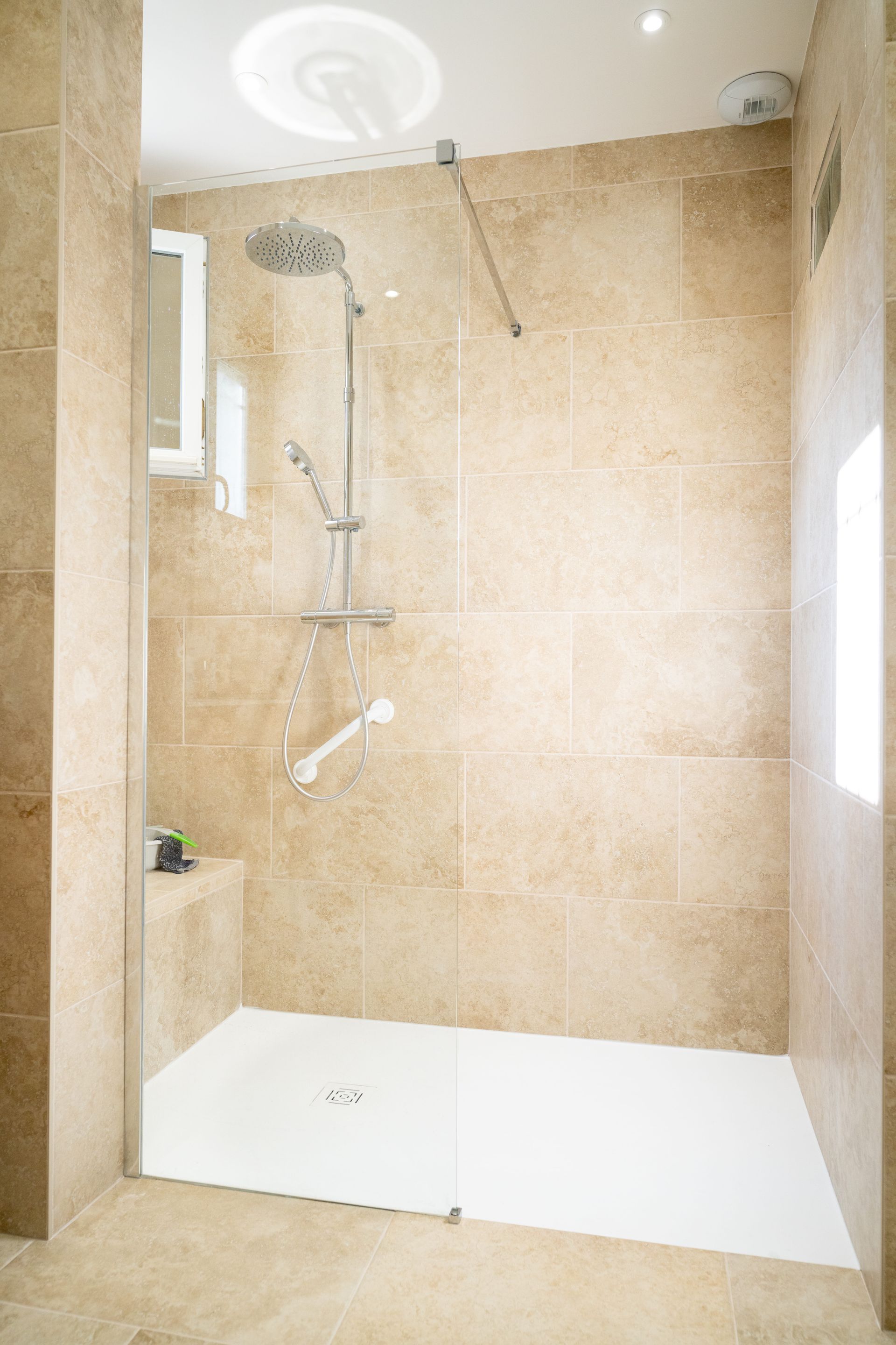 Une douche à l'italienne avec colonne de douche et barre d'appui.