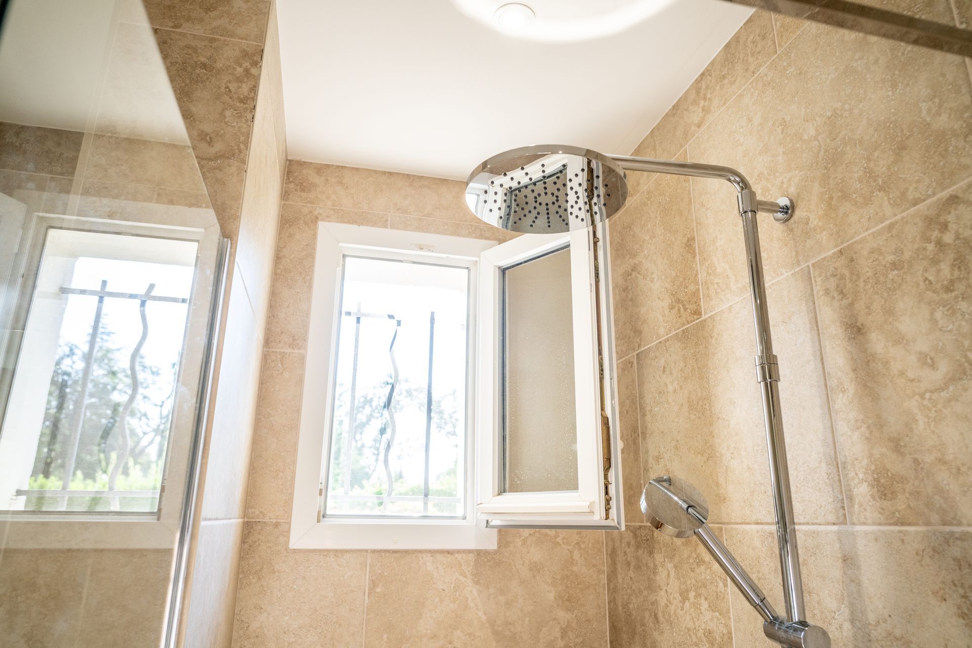 Une colonne de douche avec une fenêtre de salle de bains ouverte.