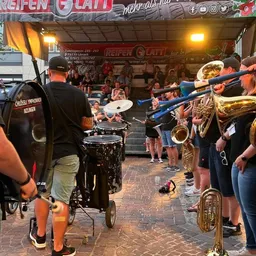 Eine Gruppe von Leuten spielt vor einer Menschenmenge Instrumente.